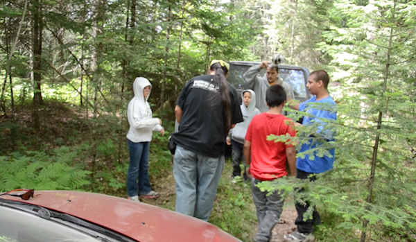 men putting on bug spray before heading out into forest