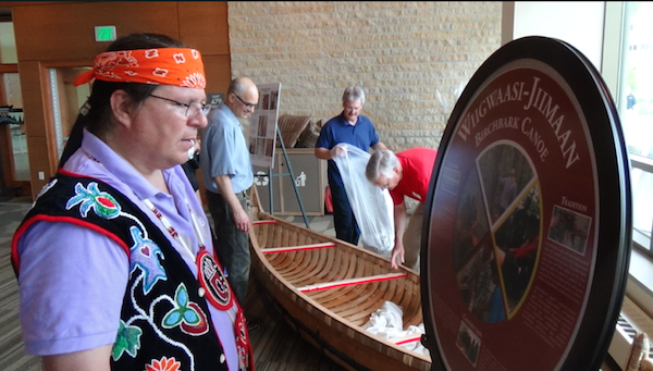 Wayne inspects sign created to commemorate canoe project at Dejope Hall