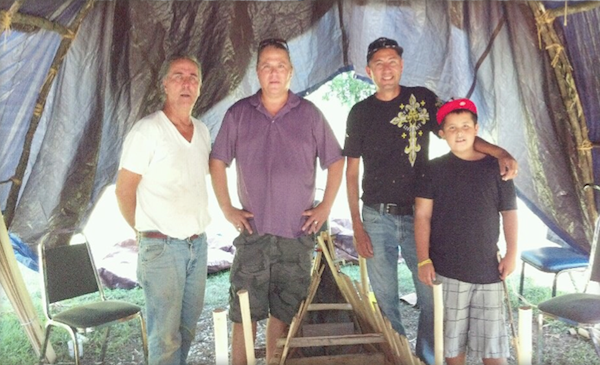 thee generations of canoe builders at work on a canoe outdoors