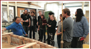 scene of Wayne speaking to class in woodshop