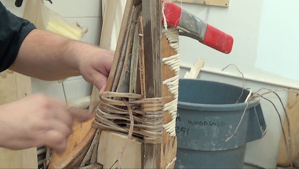 Wayne using spruce root to decorate prow