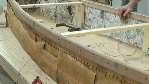 Sewing side panels partly done on one side of the canoe