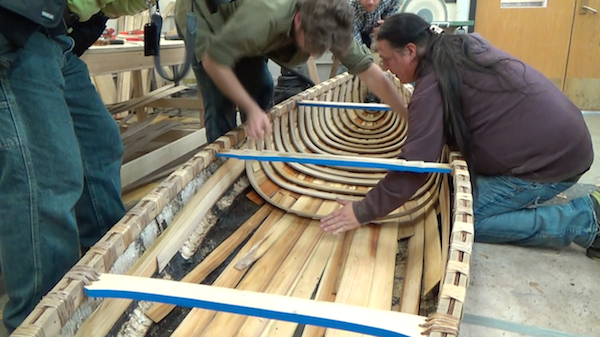 sheathing being added at middle of canoe, underneath ribs