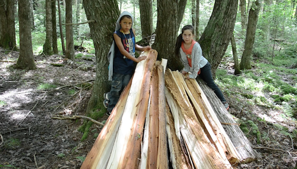 stack of newly split cedar logs makes nice place to sit for two students